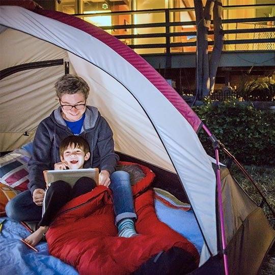 Two boys streaming content on a tablet over fixed wireless inside a tent in their backyard